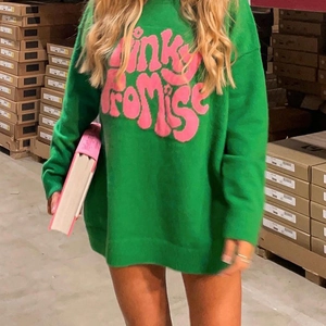 Detail of green oversized knit sweater with pink Pinky Promise letter jacquard design