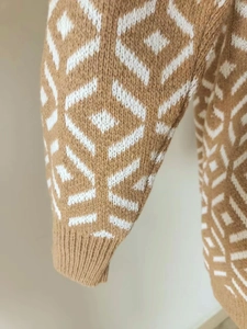 Close-up of knit sweater sleeve with brown and white geometric diamond patterns and ribbed cuff