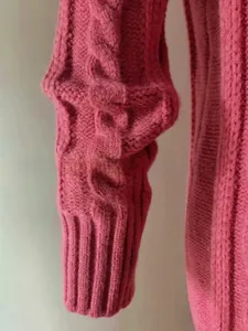 Close-up of cable knit texture and long ribbed cuffs on magenta oversized cardigan