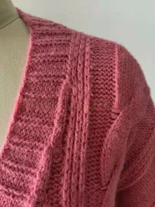 Close-up detail of mauve chunky cable knit cardigan with vertical ribbed texture