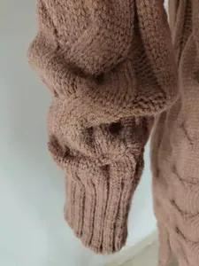 Close-up of chunky cable knit texture and ribbed cuff on a thick camel cardigan