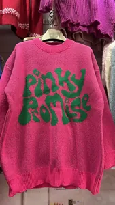 Close-up of pink knit sweater with green Pinky Promise lettering and textured knit fabric