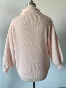 Detailed close-up of light pink chunky knit sweater featuring soft vertical ribbed texture