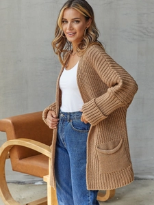 Detail of camel chunky knit cardigan featuring large patch pockets and folded cuffs
