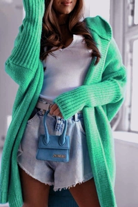 Close-up of green long sleeve knit cardigan with coarse ribbed texture and blue handbag