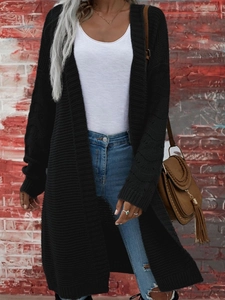 Dettaglio della trama a maglia del cardigan lungo nero con sfondo industriale urbano