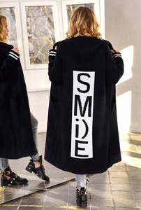 Dettaglio del lungo cardigan nero con cappuccio e stampa SMILE bianca sul retro e polsini