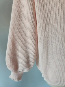 Close-up of pink cable knit sweater sleeve showing chunky texture and ribbed cuffs