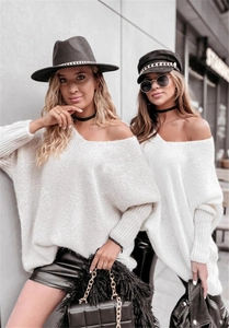 Close-up of white loose-fit knit sweater with off-shoulder V-neck and tight fabric texture