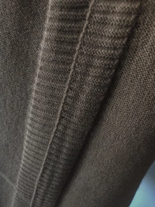 Detail of dark brown knit sweater showing fine ribbed texture and premium stitching