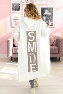 Dettaglio del lungo cardigan bianco con cappuccio e scritta SMILE marrone sul retro