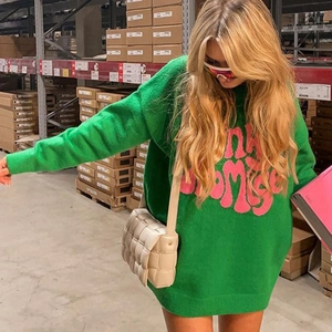 Oversize bright green knit sweater with pink Promise text and casual beige woven bag