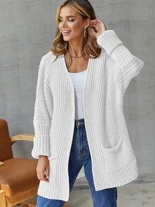 Detail of white chunky knit long cardigan featuring large front pockets and cozy texture