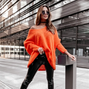 Detail of oversized orange off-shoulder knit sweater with V-neck and casual batwing sleeves