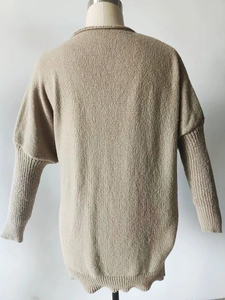 Detailed back view of a khaki knit sweater featuring batwing sleeves and ribbed edges
