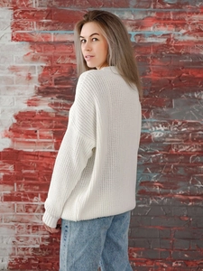 Detail view of white chunky knit sweater showing the loose fit and ribbed sleeve texture