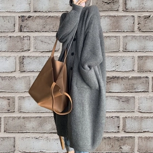 Detail of oversized dark grey knit cardigan featuring black buttons and large pockets