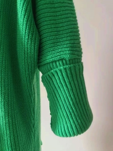 Detailaufnahme der grünen Grobstrickjacke mit Rippbündchen und Strukturstrickmuster