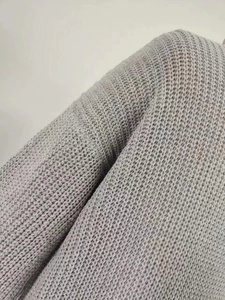 Close-up detail of light gray chunky knit texture on lantern sleeve cardigan