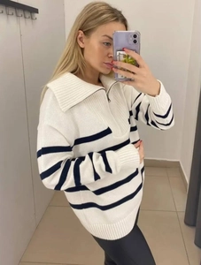 Detailed view of striped knit sweater featuring a silver half-zip collar and ribbed texture