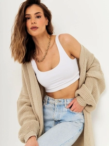 Detail of chunky beige oversized knit cardigan with soft texture and gold chain necklace