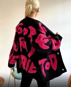 Détail du lettrage graffiti rose sur un cardigan en maille noir avec broderie texturée