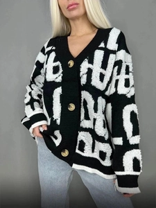 Détail du cardigan en maille à col en V avec lettres graffitis noir et blanc et boutons ambre