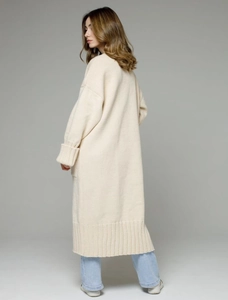 Close-up of beige knit cardigan showing ribbed cuffs and textured long-line hem