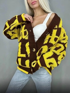 Détail du cardigan à col en V avec maille épaisse et jacquard à lettres jaunes en relief