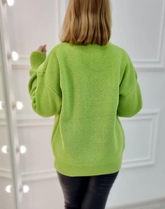 Detail view of lime green knit sweater featuring ribbed cuffs and a round neckline