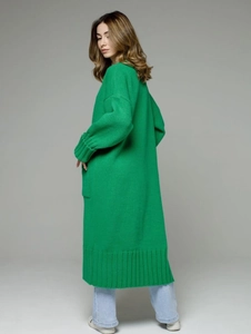 Detail view of the emerald green knit cardigan showing ribbed cuffs and textured fabric