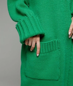Detail of bright green chunky knit cardigan with ribbed cuffs and a large patch pocket