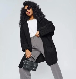 Detailed view of black chunky knit cardigan with large pockets and loose fit silhouette
