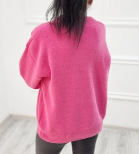 Detailed view of the pink knitted sweater featuring ribbed cuffs and relaxed drop shoulders