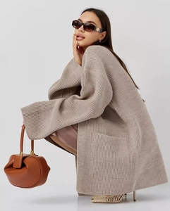 Detail showing the thick knit texture and front pocket of this beige oversized cardigan