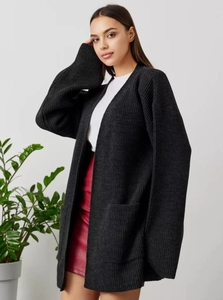 Detail of loose black chunky knit cardigan with functional pockets and drop shoulders