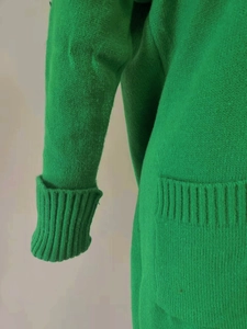 Macro detail of bright green knit cardigan showing ribbed cuffs and side pocket texture
