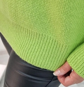 Detailed macro view of vibrant green knit sweater showing soft ribbed texture and plush fabric