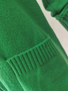 Detailed macro view of the vibrant green knit texture and ribbed hem on the long cardigan