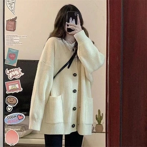 Détail du cardigan en maille beige avec de gros boutons noirs et des poches amples