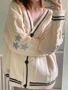 Detail of star embroidery and contrast striped trim on a chunky beige knit cardigan