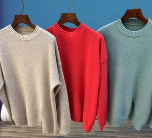 Detailed close-up of ribbed crewneck and cuffs on three colors of knit sweaters