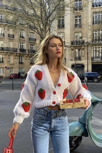 Detail of chunky knit white cardigan featuring 3D strawberry patterns and red buttons
