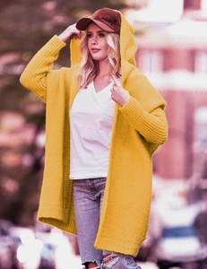 Outdoor street view of yellow hooded knit cardigan with chunky texture and batwing sleeves