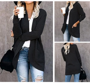 Detail of a long black waffle knit cardigan featuring an open front and side pockets