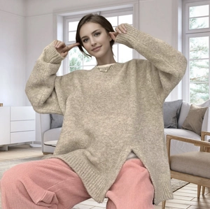 Detail of loose beige knit sweater featuring a stylish side slit and mohair texture