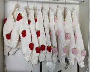 Close-up of handmade chunky knit cardigan with 3D strawberry crochet and V-neckline