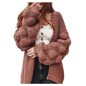 Détail d'un cardigan en grosse maille avec pompons texturés sur les manches lanterne