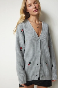 Nahaufnahme der grauen Strickjacke mit V-Ausschnitt und feinen Blumenstickerei-Details