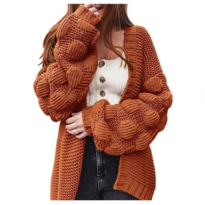Gros plan détaillé du cardigan en grosse maille orange citrouille avec manches bouffantes à pompons
